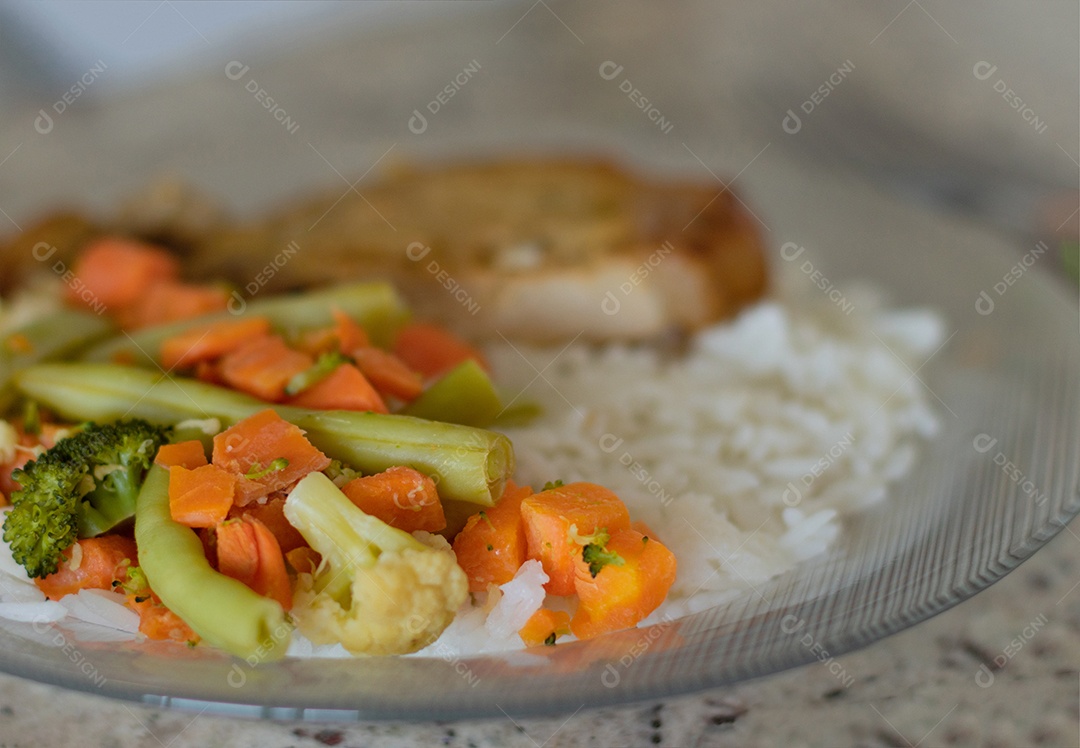 Prato com arroz e feijão e costelinha de porco na bancada.