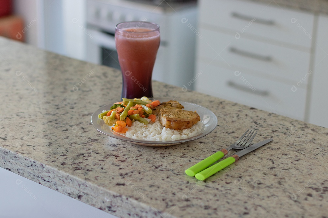 Prato com arroz e feijão e costelinha de porco na bancada.