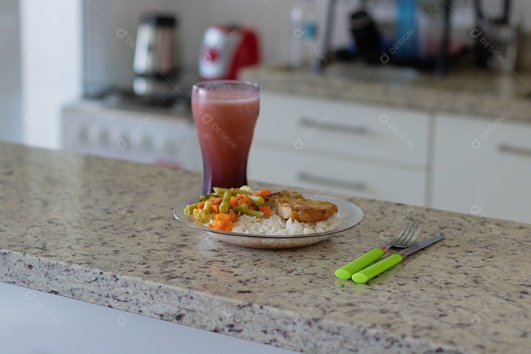 Prato com arroz e feijão e costelinha de porco na bancada.