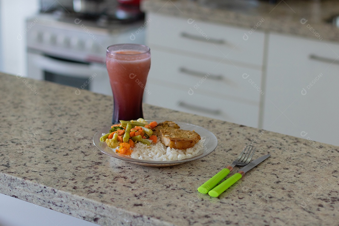 Prato com arroz e feijão e costelinha de porco na bancada.
