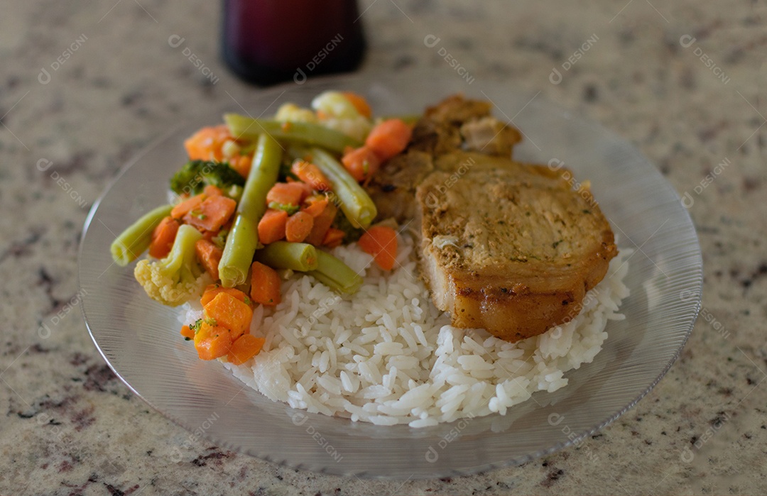 Prato com arroz e feijão e costelinha de porco na bancada.