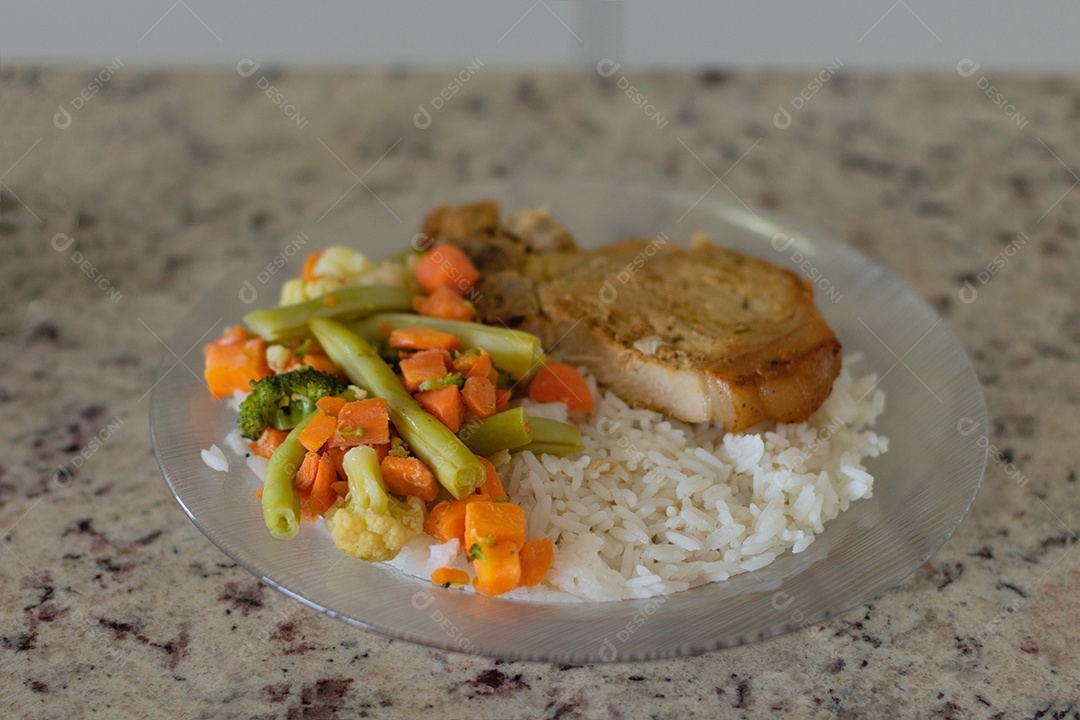 Prato com arroz e feijão e costelinha de porco na bancada.