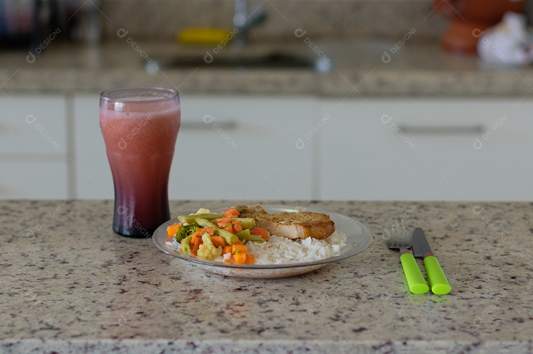 Prato com arroz e feijão e costelinha de porco na bancada.