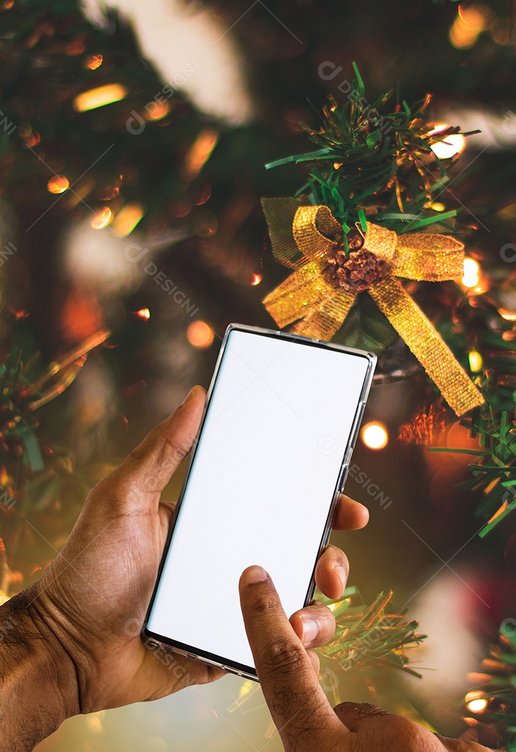 Segurando um celular em um fundo de Natal. Mãos negras com tela de celular