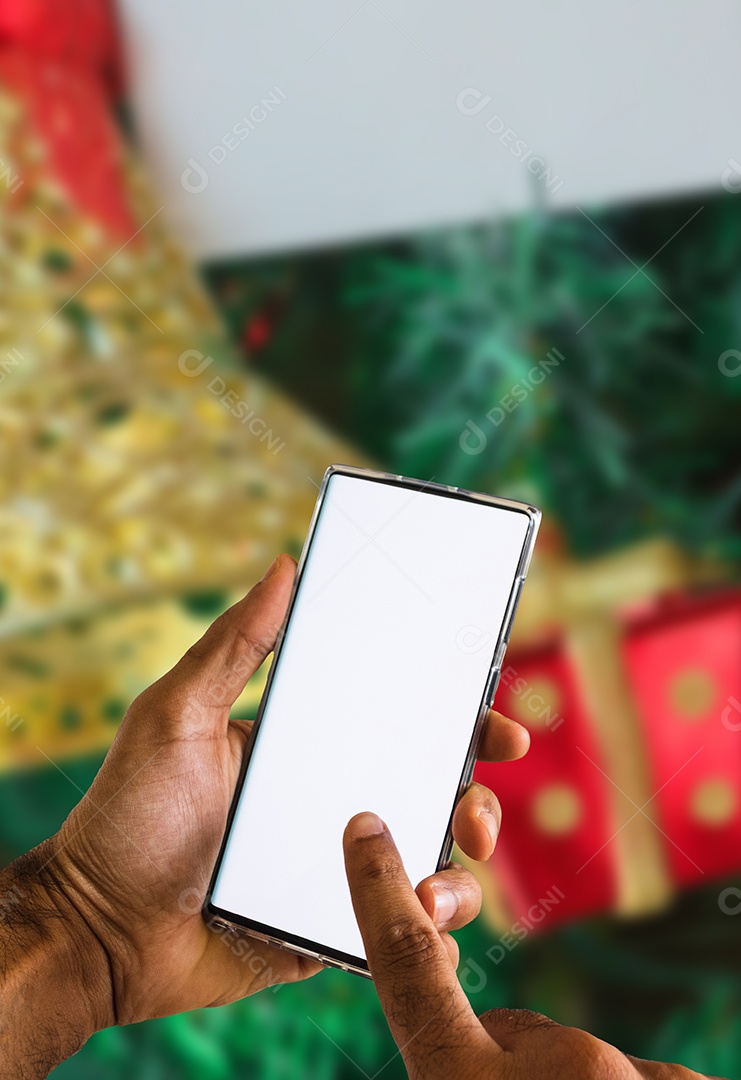Segurando um celular em um fundo de Natal. Mãos negras com tela de celular