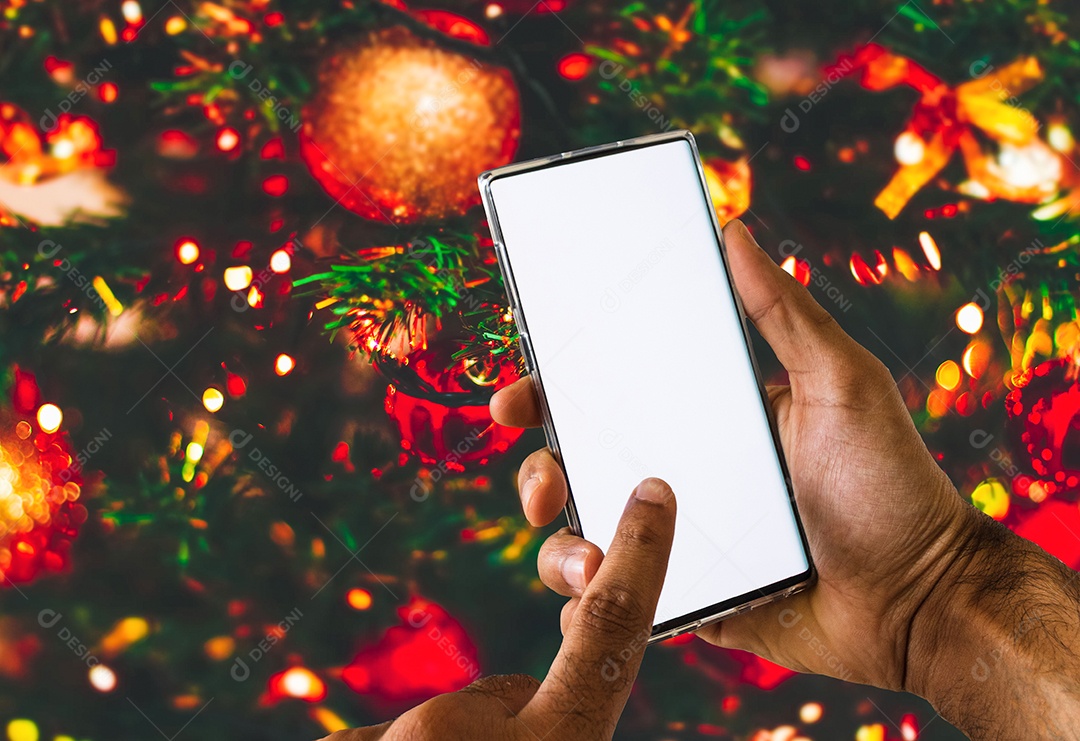 Segurando um celular em um fundo de Natal. Mãos negras com tela de celular