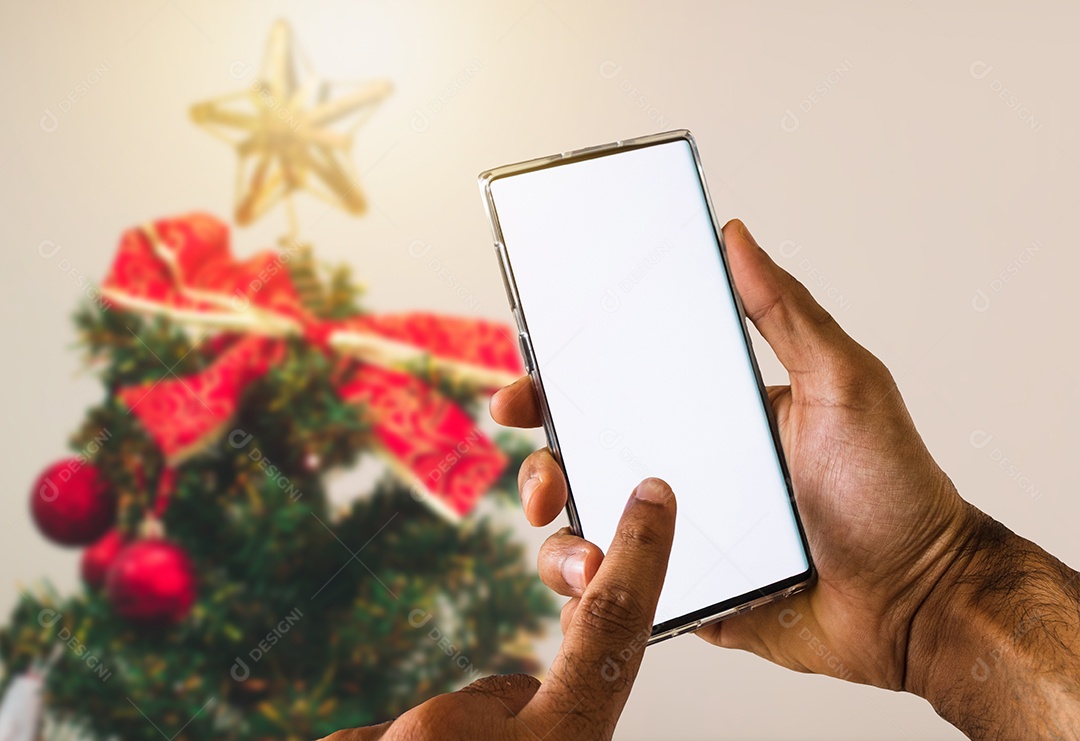 Holding a cellphone on a Christmas background. Black hands with cellphone screen