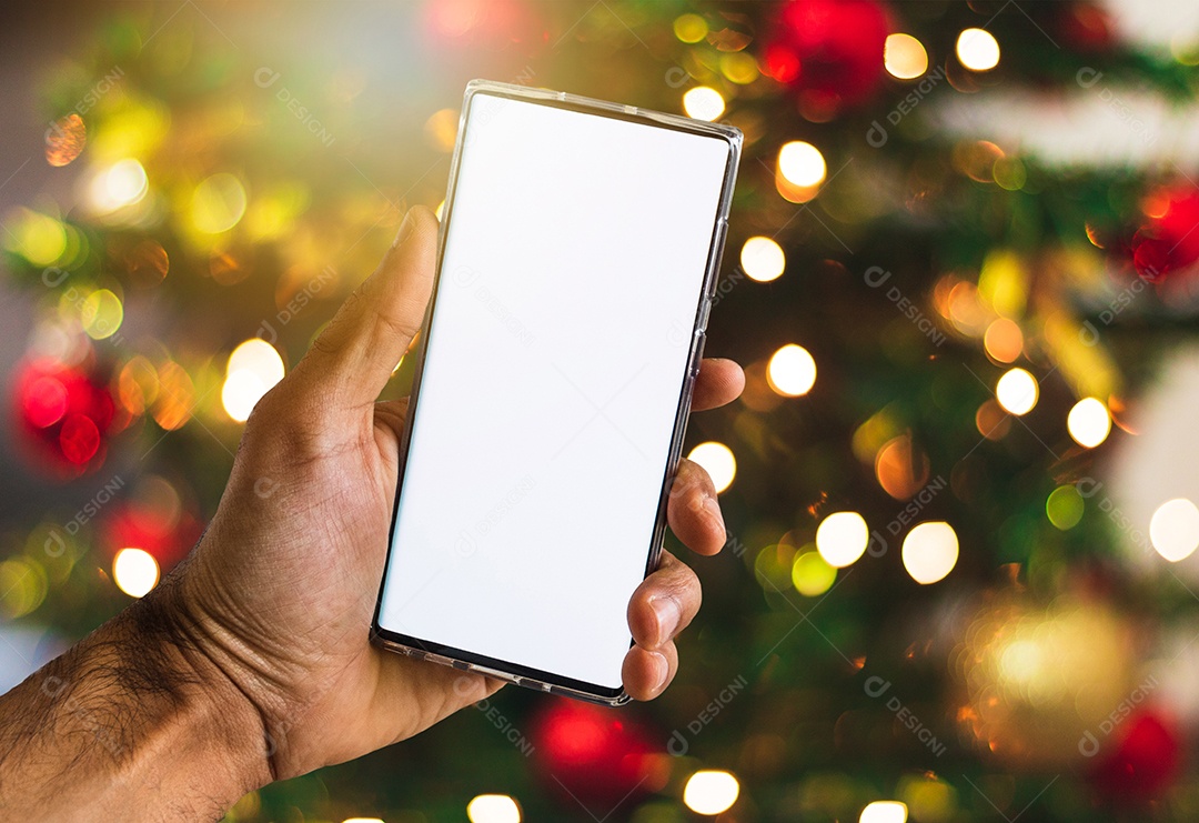 Segurando um celular em um fundo de Natal. Mãos negras com tela de celular