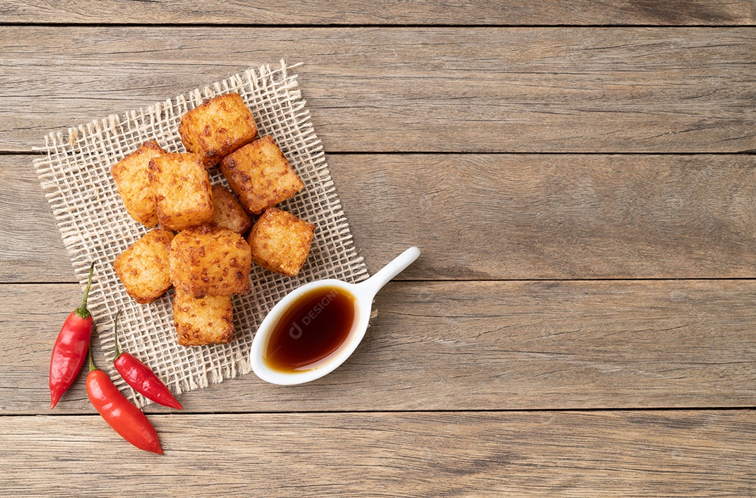 Dado de tapioca, comida com calda de pimenta malagueta sobre mesa de madeira.