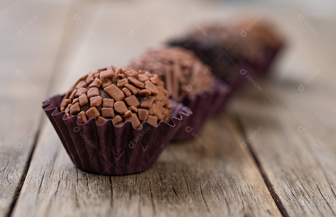 Típicos brigadeiros de chocolate brasileiros sobre mesa de madeira, profundidade de campo curta.