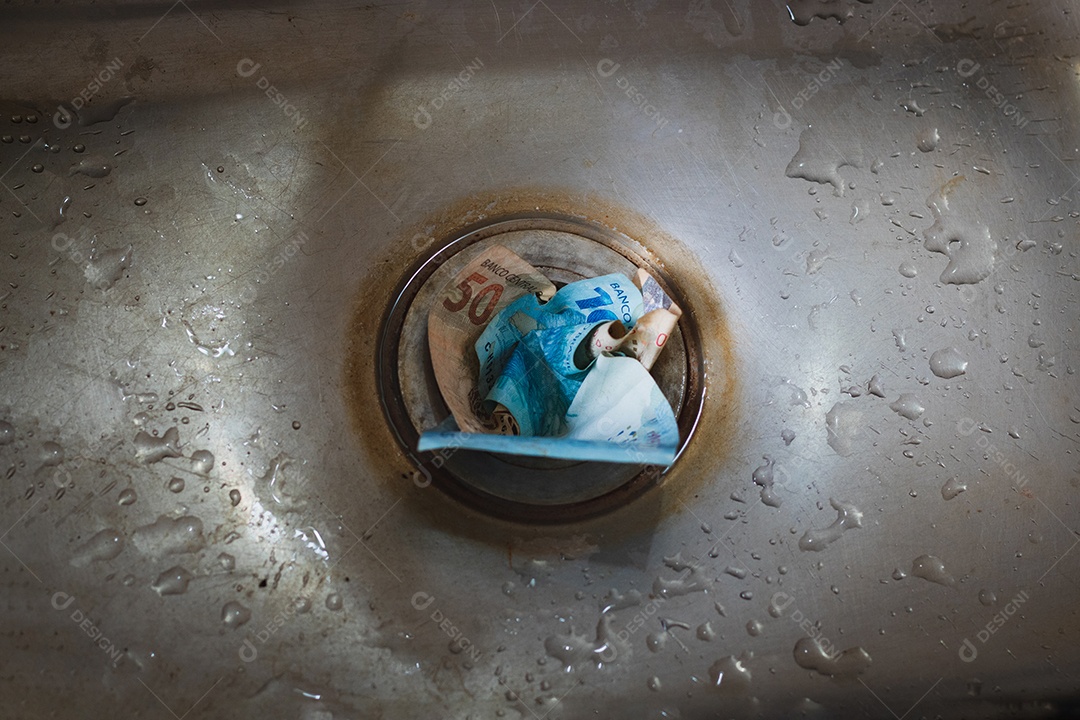Dinheiro jogado no ralo da pia cinza