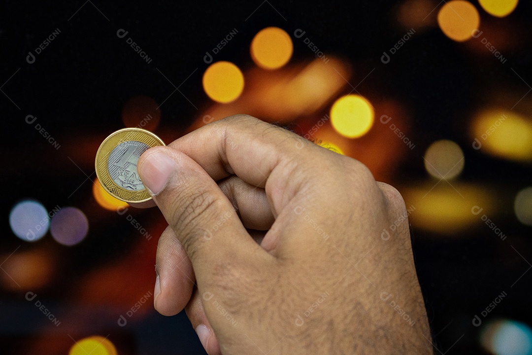 Segurando uma moeda brasileira em um fundo desfocado