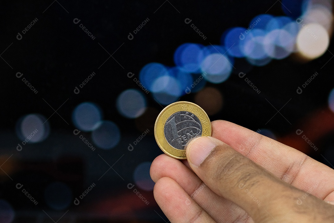 Segurando uma moeda brasileira em um fundo desfocado