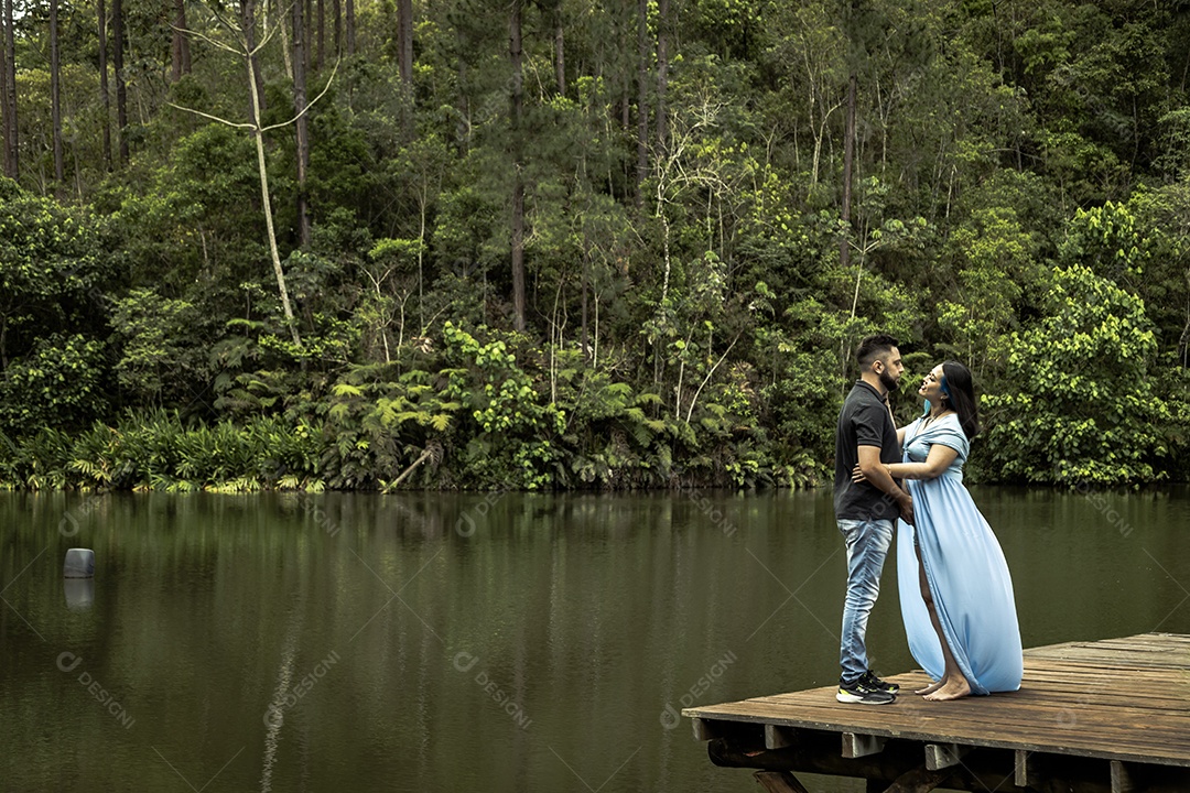 Homem com ao lado de sua esposa gravida sobre linda paisagem