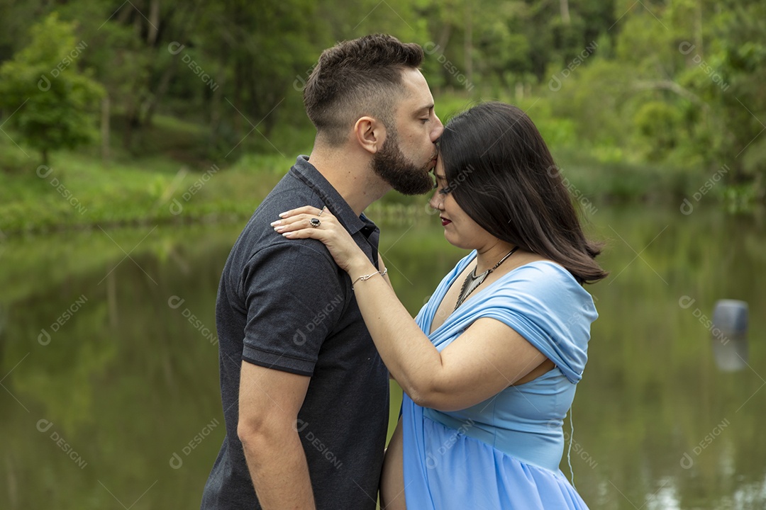 Homem com ao lado de sua esposa gravida sobre linda paisagem