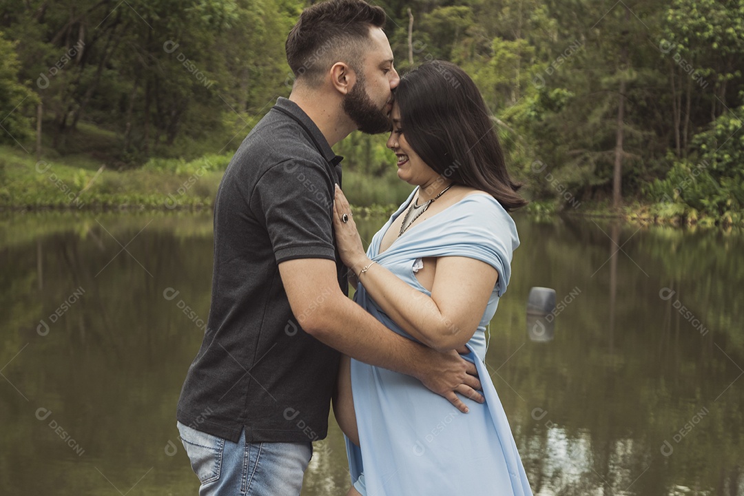 Homem com ao lado de sua esposa gravida sobre linda paisagem