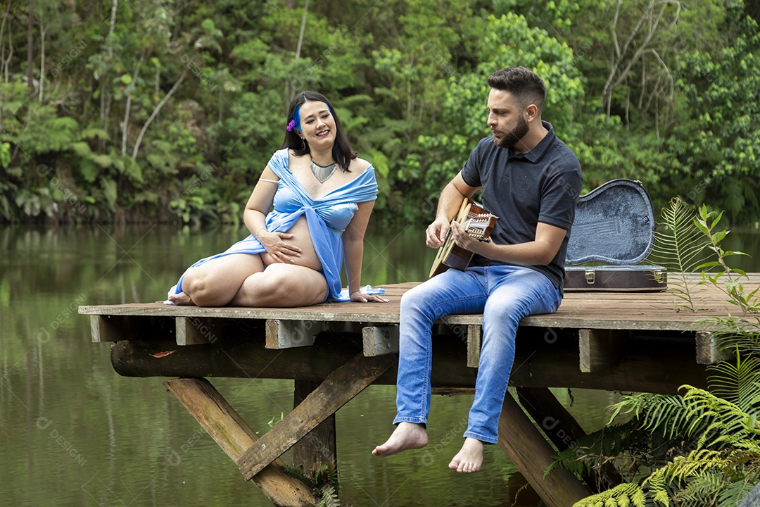 Homem com ao lado de sua esposa gravida sobre linda paisagem