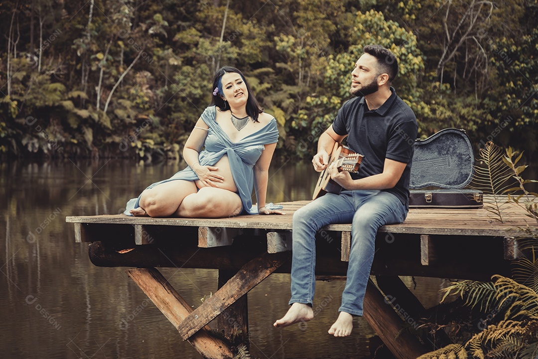 Homem com ao lado de sua esposa gravida sobre linda paisagem