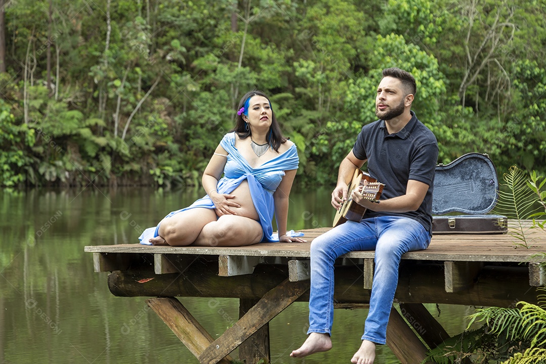 Homem com ao lado de sua esposa gravida sobre linda paisagem