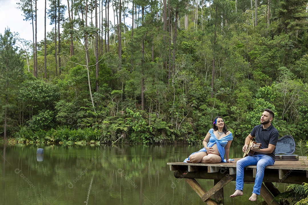 Homem com ao lado de sua esposa gravida sobre linda paisagem