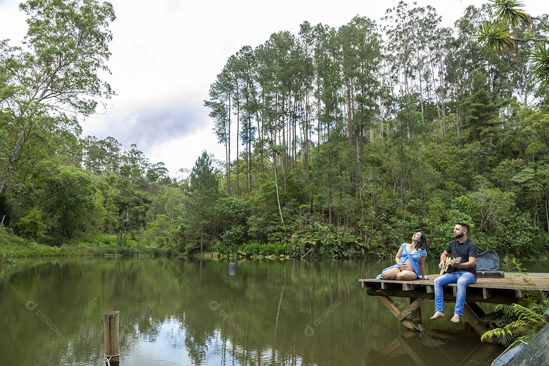 Homem com ao lado de sua esposa gravida sobre linda paisagem