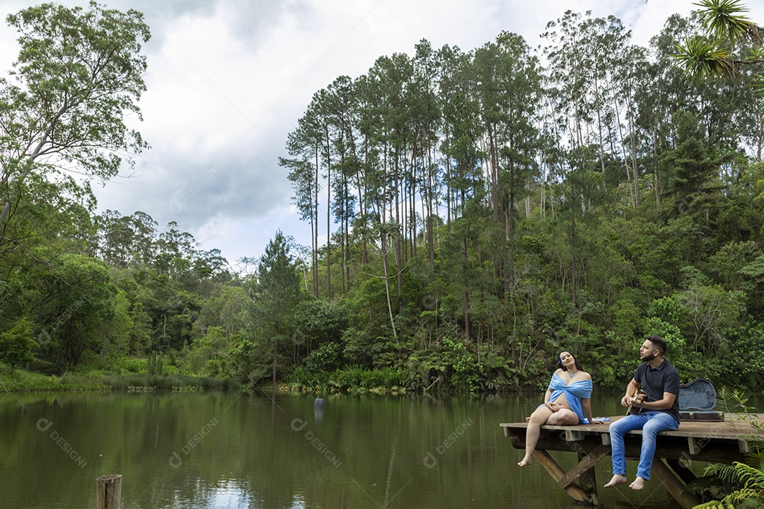 Homem com ao lado de sua esposa gravida sobre um lindo lugar paisagem
