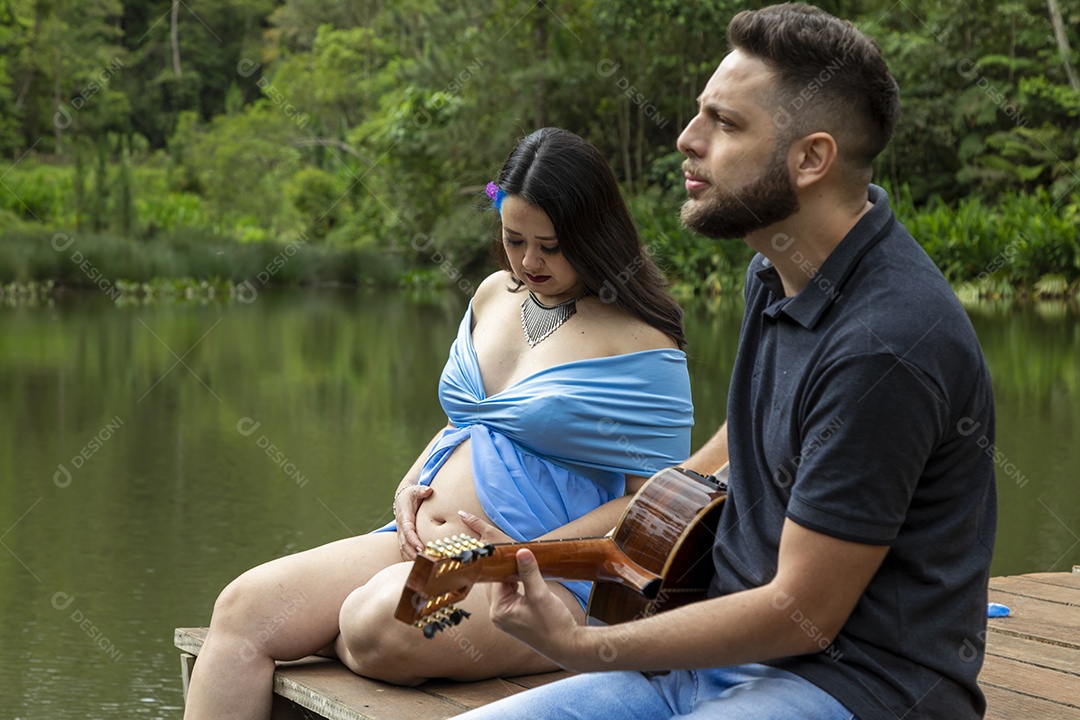 Homem com ao lado de sua esposa gravida sobre um lindo lugar paisagem