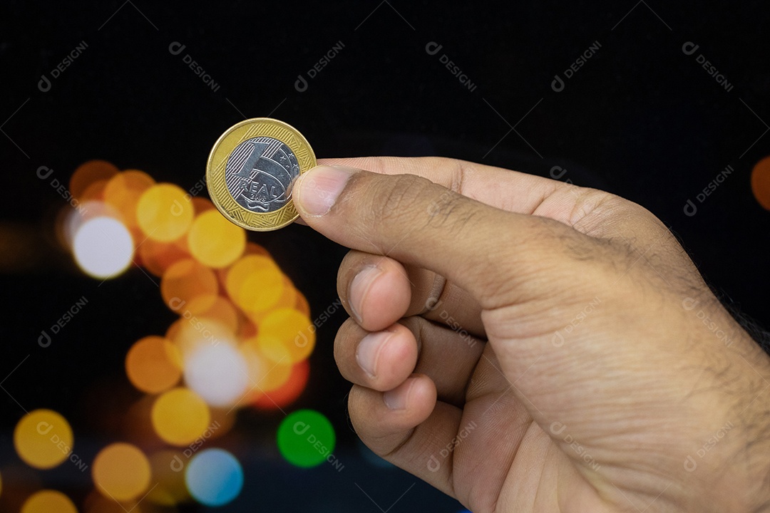 Segurando uma moeda brasileira em um fundo desfocado