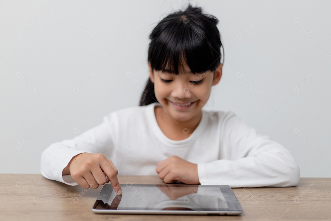 Menina bonitinha asiática tocando a tela do tablet digital no