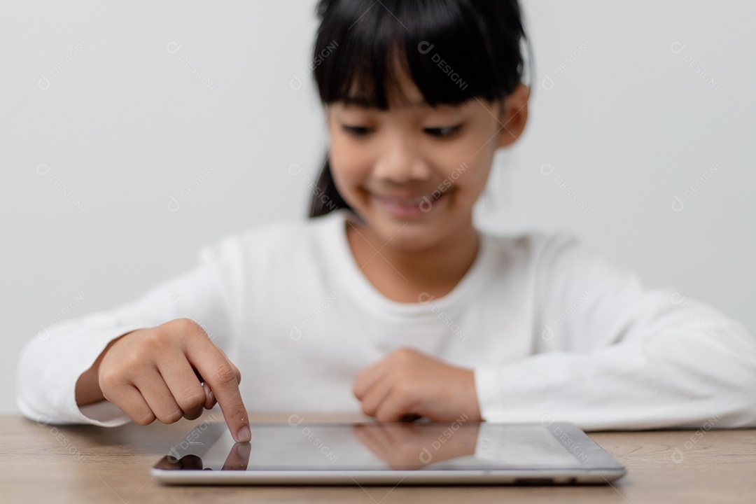 Menina bonitinha asiática tocando a tela do tablet digital no