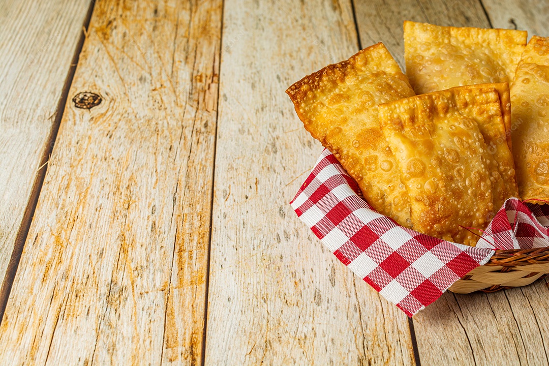 Pastel brasileiro, lanche frito em uma tigela ou recipiente, sobre mesa de madeira