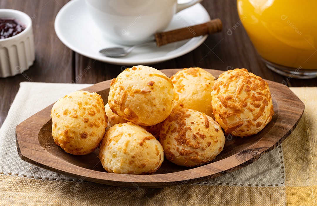 Pão de queijo típico brasileiro em um prato sobre a mesa de madeira.