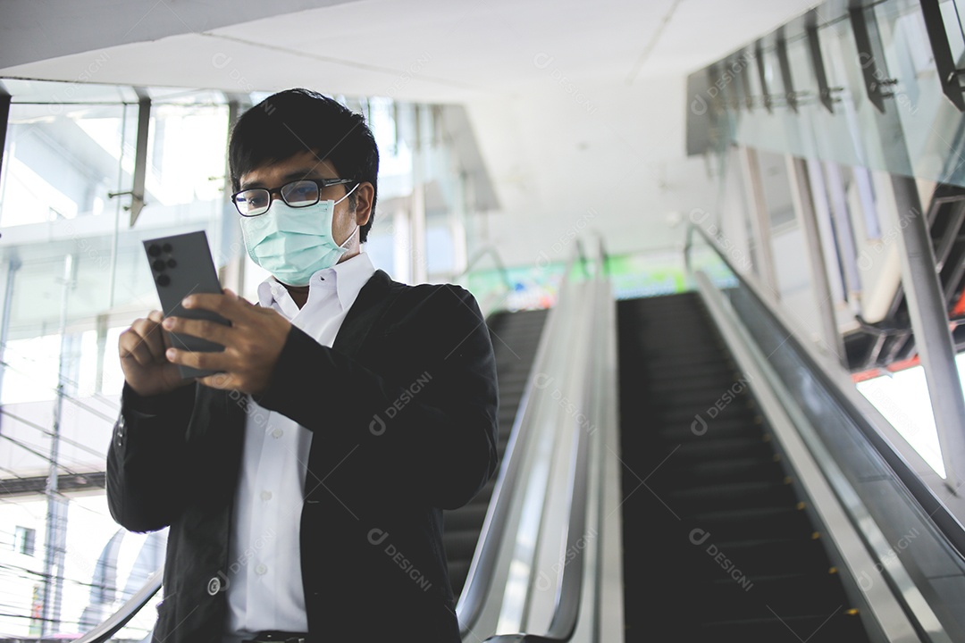 Freelancer masculino asiático usando máscara cirúrgica indo trabalhar de manhã no metrô