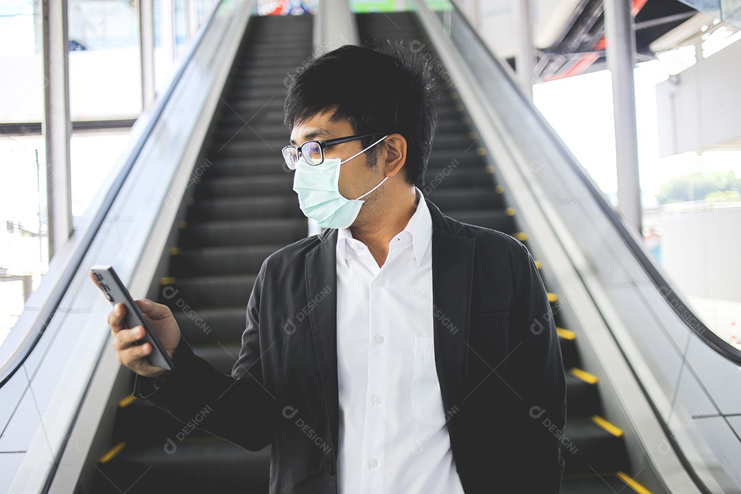 Freelancer masculino asiático usando máscara cirúrgica indo trabalhar de manhã no metrô