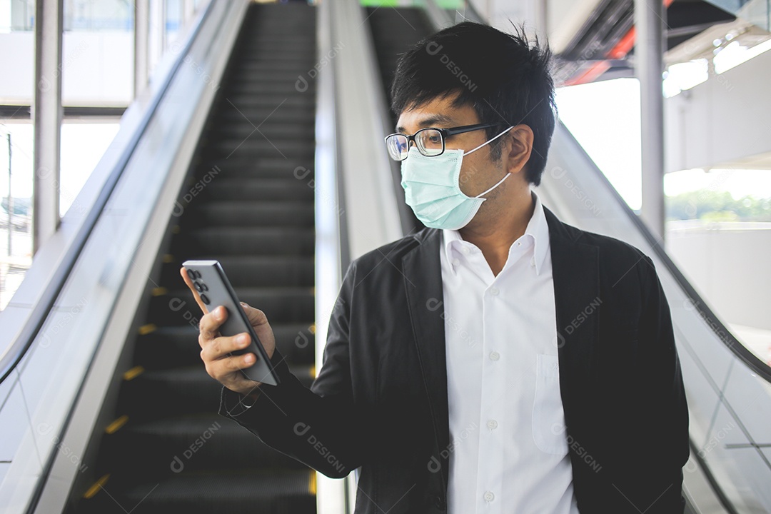 Freelancer masculino asiático usando máscara cirúrgica indo trabalhar de manhã no metrô.