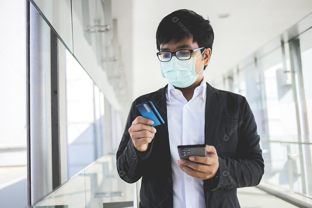 Homem de negócios asiáticos em óculos e usando máscara cirúrgica pagando