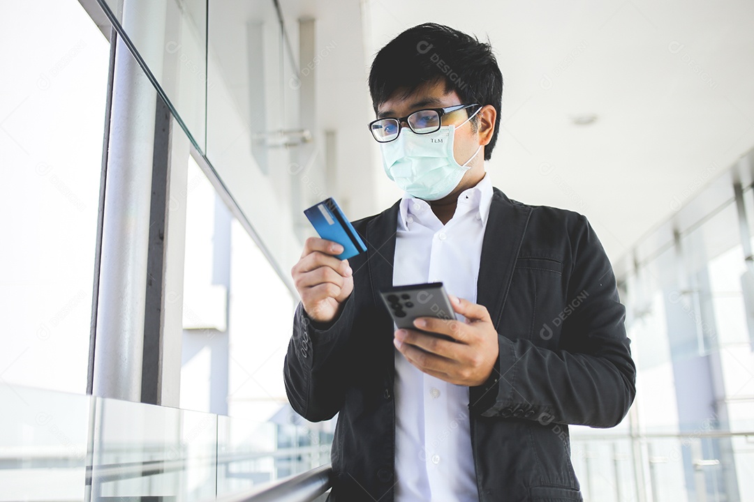 Homem de negócios asiáticos em óculos e usando máscara cirúrgica pagando