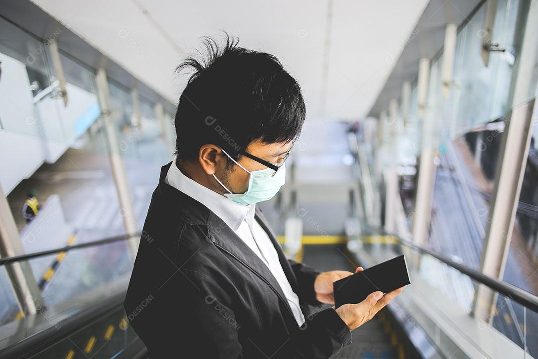 Um jovem empresário bonito asiático usando seu telefone e de pé