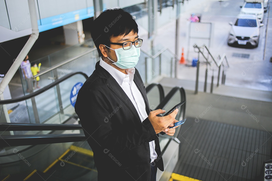 Um jovem empresário bonito asiático usando seu telefone e de pé