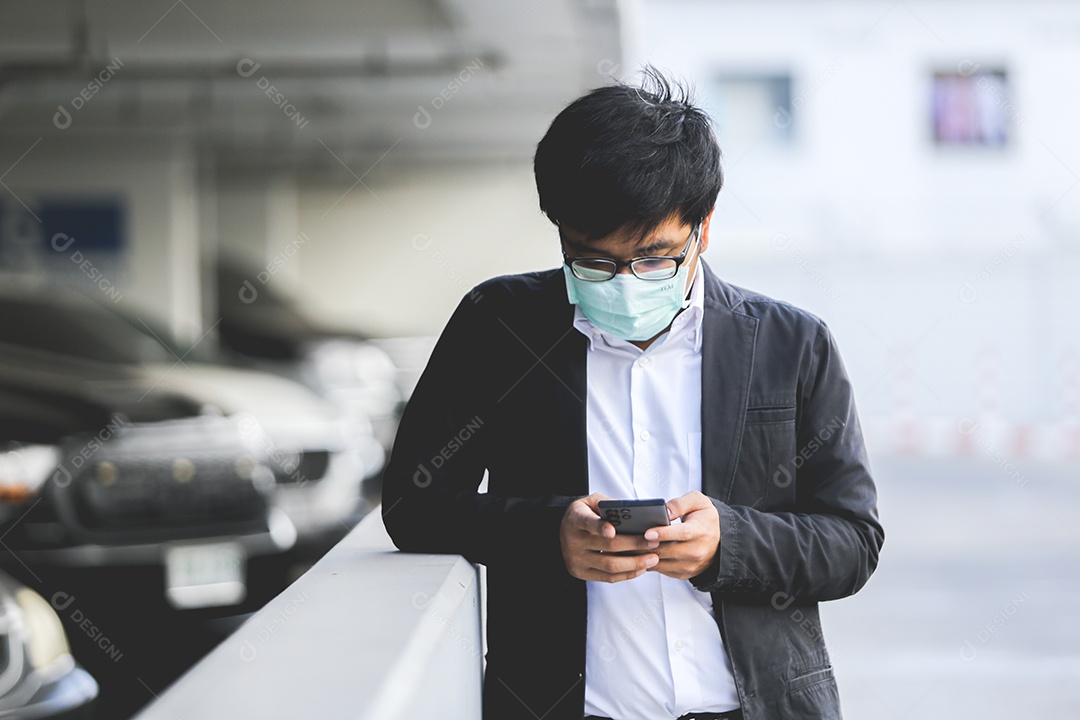 Um jovem empresário bonito asiático usando seu telefone e de pé