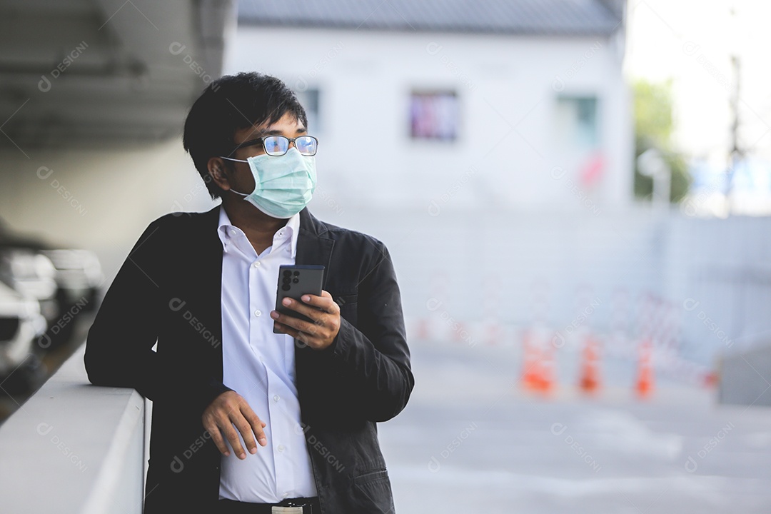 Um jovem empresário bonito asiático usando seu telefone e de pé