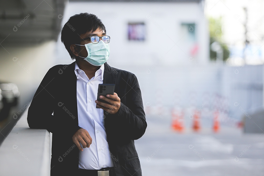 Um jovem empresário bonito asiático usando seu telefone e de pé