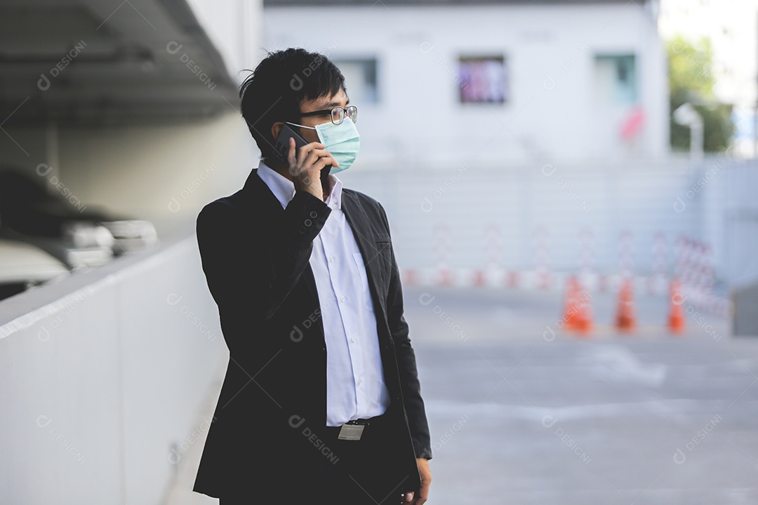 Homem asiático de máscara falando no celular