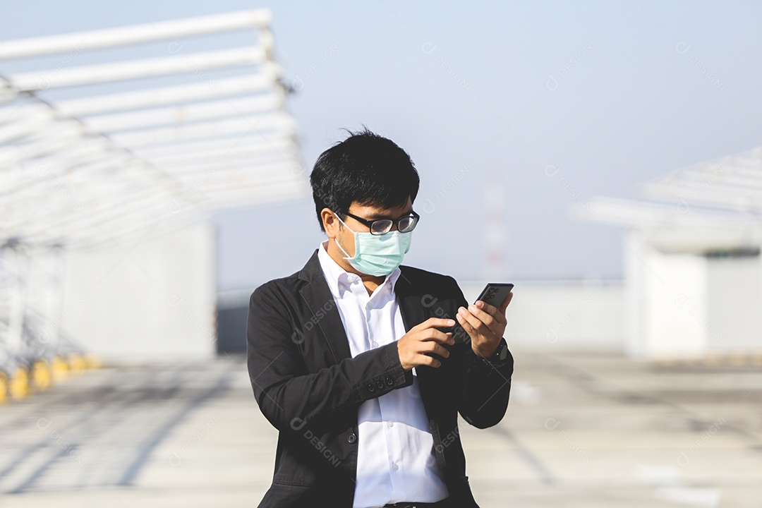 Homem asiático de máscara usando celular