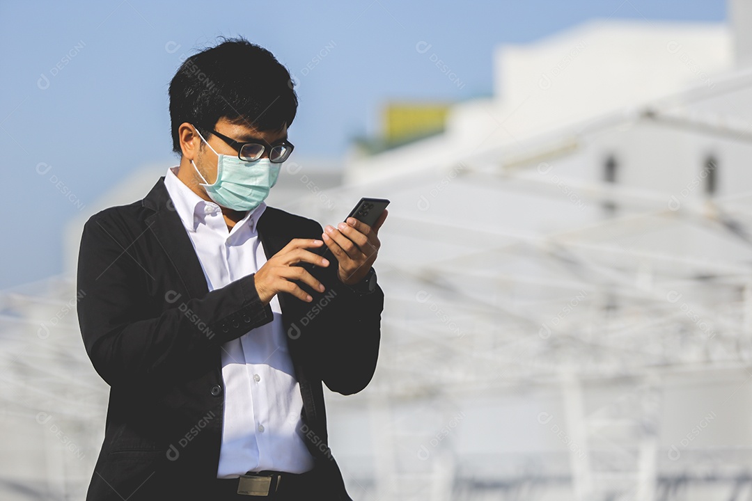 Homem asiático de máscara usando celular