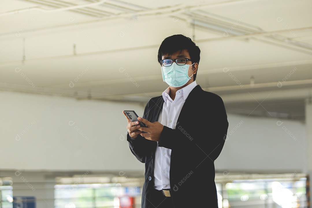 Homem asiático de máscara usando celular