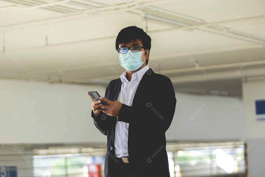 Homem asiático de máscara usando celular