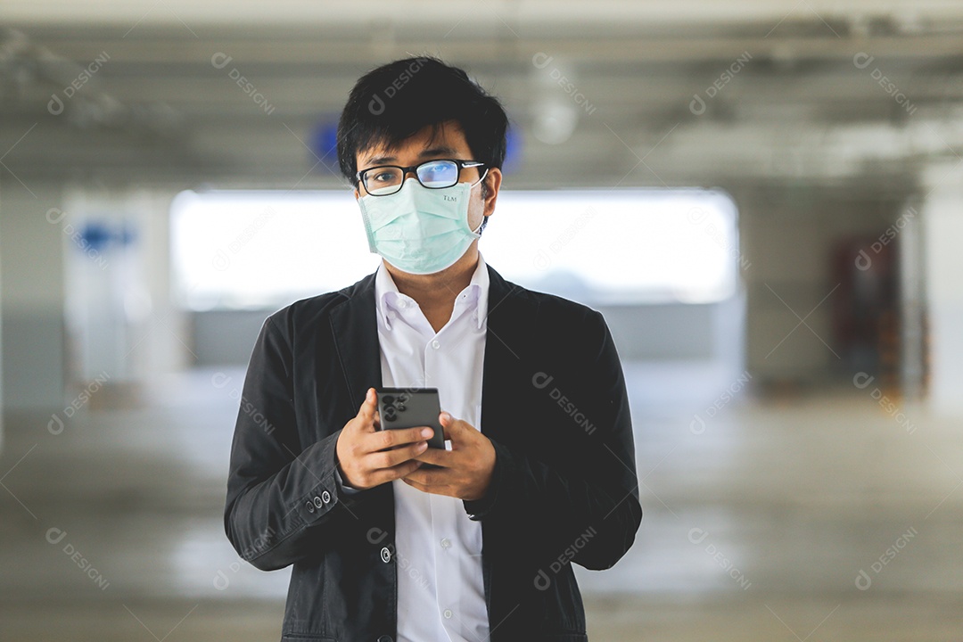 Homem asiático de máscara usando celular