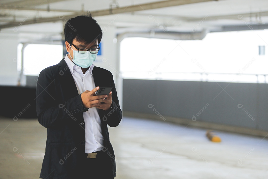 Homem asiático de máscara usando celular