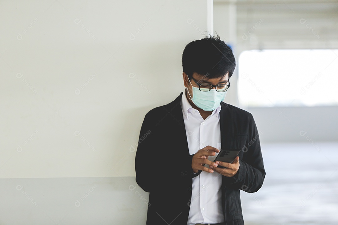 Homem asiático de máscara usando celular